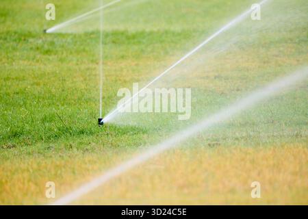 Nahaufnahme von Sprinklern, die den Rasen eines öffentlichen Parks bewässern. Stockfoto