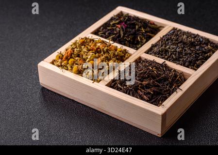 Eine Holzkiste mit verschiedenen Arten von getrocknetem Tee, grünem, schwarzem, Obst und Kamille. Trockener Tee in der Schachtel Stockfoto