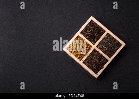 Eine Holzkiste mit verschiedenen Arten von getrocknetem Tee, grünem, schwarzem, Obst und Kamille. Trockener Tee in der Schachtel Stockfoto