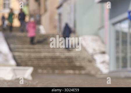 Verschwommene urbane Straßenszene mit Menschen auf Stufen im winterlichen Stadtbild Stockfoto