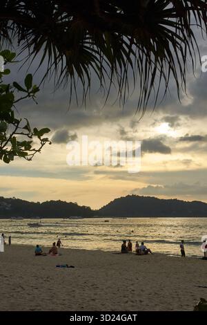Malerischer Blick auf den Sonnenuntergang auf einen tropischen Strand mit entspannenden Menschen am Sandstrand Stockfoto