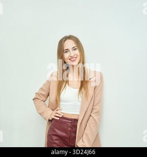 Fröhliche junge kaukasische Frau in stilvollem Outfit, die selbstbewusst lächelt Stockfoto