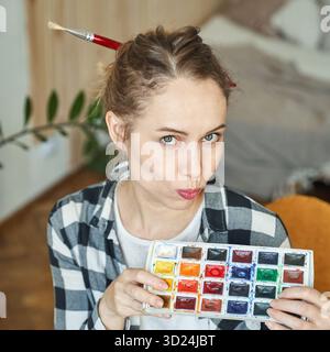 Junge kaukasische Künstlerin mit Aquarellpalette und Pinselhaar Stockfoto