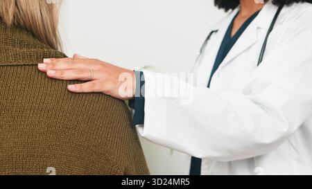 Der Arzt bietet eine sanfte Schulterkontrolle und Pflege für den Patienten während der medizinischen Beratung Stockfoto