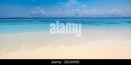 Entspannendes, sonniges Strandpanorama mit ruhigem, blauem Himmel und weichem Sand aus der Nähe. Friedliche Sommeratmosphäre mit Küstenlandschaft. Inspirierende Natur Stockfoto