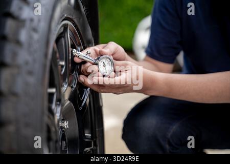 Nahaufnahme eines Reifendruckmanometers, das den Luftdruck eines Autoreifens überprüft und dabei die Fahrzeugwartung und -Sicherheit betont. Stockfoto