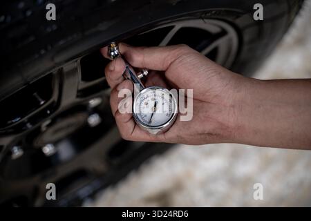 Nahaufnahme eines Reifendruckmanometers, das den Luftdruck eines Autoreifens überprüft und dabei die Fahrzeugwartung und -Sicherheit betont. Stockfoto