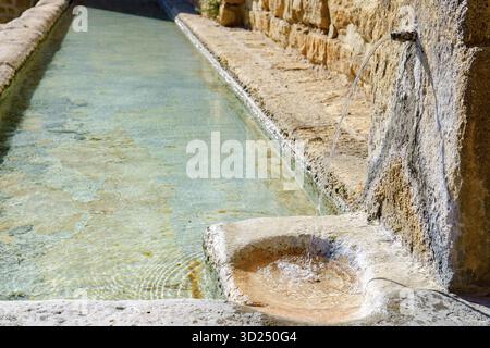 Ronda, malaga, spanien frisches, klares Wasser, das von einem alten Steinauslauf in einen historischen, rustikalen Trog fließt, erzeugt sanfte Wellen in ronda, malaga, spanien Stockfoto