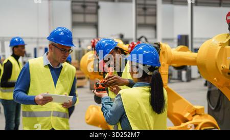 Multirassische Menschen, die in einer Maschinenbaufabrik arbeiten – Technologie, maschinelles Lernen, KI und Industriekonzept – konzentrieren sich auf Mädchenhelme Stockfoto