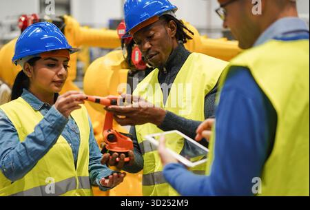 Multirassische Menschen, die in einer Maschinenbaufabrik arbeiten – Technologie, maschinelles Lernen, KI und Industriekonzept – konzentrieren sich auf das afrikanische Männergesicht Stockfoto