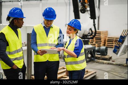 Multirassische Menschen, die in einer Maschinenbaufabrik arbeiten – Technologie, maschinelles Lernen, KI und Industriekonzept – konzentrieren sich auf das Frauengesicht Stockfoto