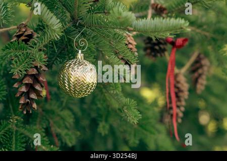 Nahaufnahme des Weihnachtsbaums mit Tannenzapfen und roten Bändern Stockfoto