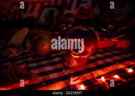 Dekorierter Zuckerschädel (Calaverita) an einem traditionellen mexikanischen Totenopfer mit dramatischer, kultureller und Erinnerungsbeleuchtung. Stockfoto