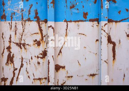 Rost und abblätternde Farbe auf einem blau-weißen Metallbehälter Stockfoto
