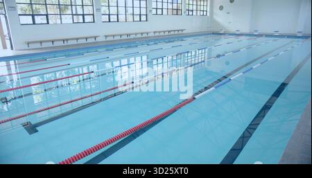 Leerer Pool in der zentralen Poolhalle, mit roten und blauen Trennwänden und Holzbank Stockfoto