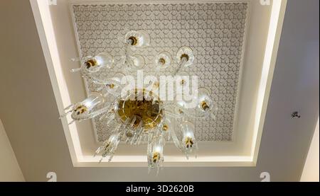 Dekorative Deckenverkleidung und ein glitzernder Kronleuchter aus braunem Glas im Innenbereich Stockfoto