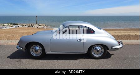 Klassisches Porsche 356 Coupé, das an der Uferpromenade mit Strand und Meer im Hintergrund geparkt ist. Stockfoto