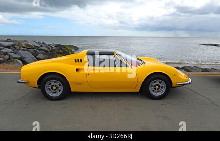 Klassischer Ferrari Dino 246 GT Wagen, der an der Strandpromenade am Strand und am Meer im Hintergrund geparkt wird Stockfoto