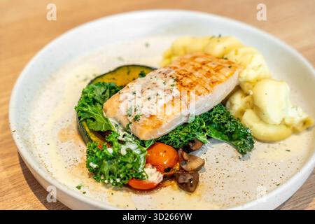 Leckeres gegrilltes Lachssteak mit Gemüse und Kartoffelpüree, serviert auf hellem Holztisch, Nahaufnahme. Stockfoto