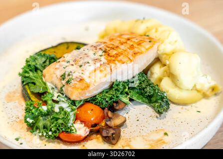 Leckeres gegrilltes Lachssteak mit Gemüse und Kartoffelpüree, serviert auf hellem Holztisch, Nahaufnahme. Stockfoto