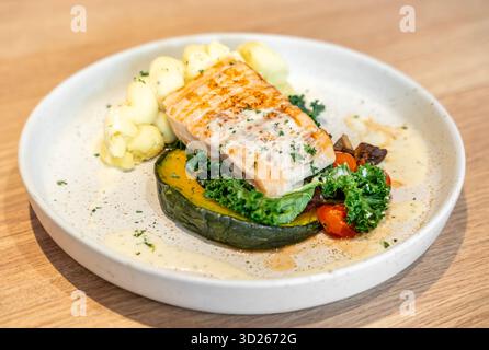 Leckeres gegrilltes Lachssteak mit Gemüse und Kartoffelpüree, serviert auf hellem Holztisch, Nahaufnahme. Stockfoto
