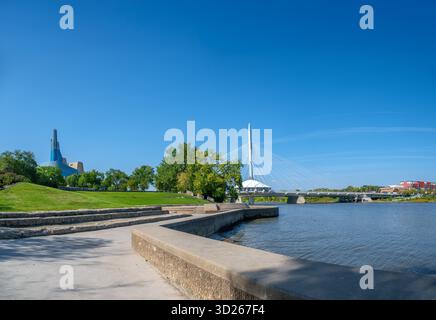 Spaziergang entlang des Red River mit Blick auf die Fußgängerbrücke Esplanade Riel und das Canadian Museum for Human Rights, The Forks, Forks National Histo Stockfoto