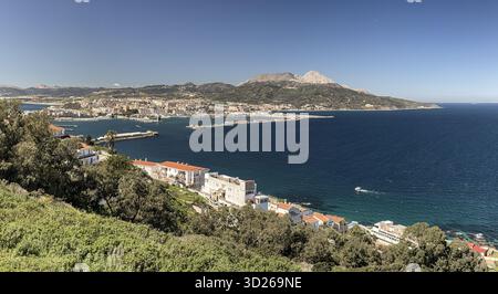Weite Küstenlandschaft mit Ceuta, Hafeninfrastruktur und bergigem Gelände dahinter. Stockfoto