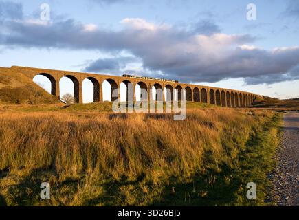 Ein Sprinter-Personenzug überquert das Ribblehead Viaduct in der Nähe von Ingleton, North Yorkshire, kurz vor Sonnenuntergang Stockfoto