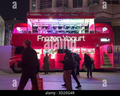 Kunden, die gefrorenen Joghurt auf dem Oberdeck eines Doppeldeckerbusses genießen, der in ein mobiles gefrorenes Joghurtgeschäft im Londoner West End umgewandelt wurde. Stockfoto