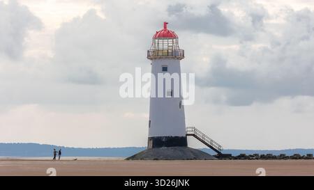 Zwei Leute, die zum Talacre Point des Ayr Leuchtturms am Strand schauen Stockfoto