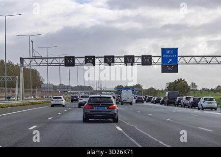 Ansicht einer mehrspurigen niederländischen Autobahn mit variablen Schildern über der Decke, die eine Geschwindigkeitsbegrenzung von 70 km/h aufgrund der Verkehrsbedingungen anzeigen. Stockfoto