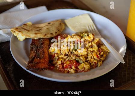 Das ist ein Top-Down-Studio-Bild einer frischen Mahlzeit, bestehend aus Eiern, Tamal, Käse und gefüllter Tortilla auf einem Teller. Stockfoto