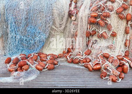 Ein großer Stapel von Fischernetzen mit Schwimmern liegt auf einem Holzsteg gesammelt. Stockfoto
