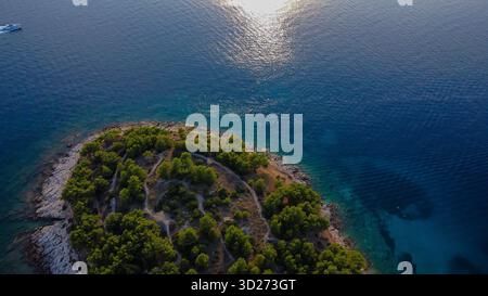 Die zerklüftete felsige Küste und das Meer übergehen von einem tiefen, sonnendurchfluteten Blau zu einem klaren, einladenden Türkis. Stockfoto
