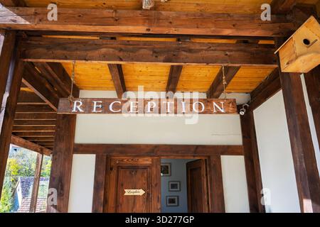 Ein hölzernes Schild an der Decke, auf dem steht "Empfang". Das Schild hängt von der Decke und ist aus Holz Stockfoto
