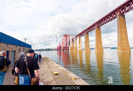 SOUTH QUEENSFERRY, SCHOTTLAND - 22. August 2025: Die berühmte Forth Bridge, die zum UNESCO-Weltkulturerbe gehört, überspannt den Firth of Forth und trägt den Eisenbahnverkehr acr Stockfoto