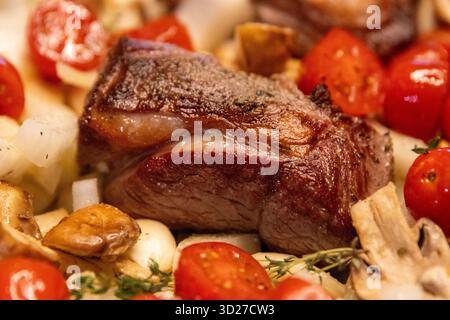 Ein Topf gebratenes Lammsteak mit Kräutern, Tomaten, Zwiebeln und Pilzen Stockfoto