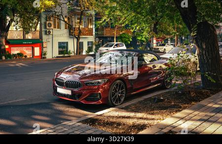 Jerewan, Armenien 10.16.2025. Ein roter BMW parkt am Straßenrand vor einem Gebäude. Das Auto steht auf einem Parkplatz neben einem Baum Stockfoto