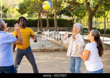 Alte multinationale Menschen spielen Volleyball-Aktivität auf einem Sommerspielplatz für Sport im Frühling draußen Stockfoto