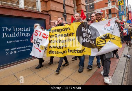Demonstranten halten ein Banner, während sie während der Demonstration auf der Straße marschieren. Die Verkehrsmittel für das streikende Greater Manchester-Personal brachten die Straßenbahnen im Stadtzentrum mit ihrem marsch und ihrer Kundgebung zum Stillstand. Streikende Arbeiter, darunter UNISON- und Unite-Mitglieder, marschierten durch das Stadtzentrum zu den Tootal-Gebäuden in der Oxford Street. Die Tootal Buildings sind der Sitz der Greater Manchester Combined Authority (GMCA) und das Büro des Bürgermeisters von Greater Manchester, der sich für bessere Löhne und Arbeitsbedingungen einsetzt. Stockfoto