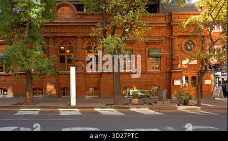 Jerewan, Armenien 10.16.2025. Ein Backsteingebäude mit einem weißen Schild auf dem Bürgersteig. Das Gebäude hat viele Fenster und einen Balkon Stockfoto
