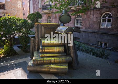 Jerewan, Armenien 10.16.2025. Eine Statue eines Buches sitzt auf einem Stapel Bücher. Die Statue besteht aus Metall und ist auf einem Bürgersteig aufgestellt. Die St Stockfoto