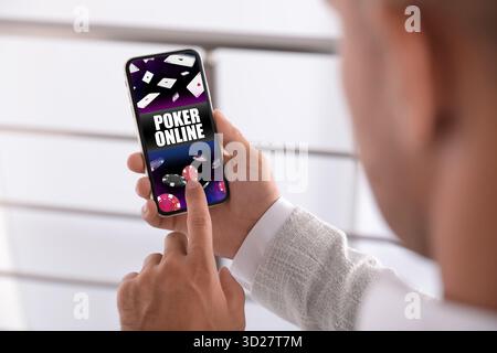 Mann, der online Poker spielt, drinnen auf dem Handy, Nahaufnahme Stockfoto