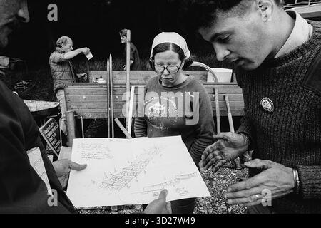 Dieses Schwarzweiß-Foto fängt einen Moment während der ersten internationalen Reise des Sierra Club nach England, Großbritannien, ein. Ein lokaler Naturschützer untersucht eingehend architektonische Pläne für Steintreppen, während ein anderer auf Details hinweist. Das Bild dokumentiert eine Zusammenarbeit, die sich auf die Naturschutzarbeit im Vereinigten Königreich konzentriert. Stockfoto