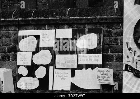 Dieses Bild zeigt ein schwarz-weißes Zeichenbrett, das an einer Ziegelwand befestigt ist, wahrscheinlich während des jährlichen Well Dressing-Events in Chesterfield, Großbritannien, aufgenommen wurde. Das Brett ist mit verschiedenen Skizzen bedeckt, die vermutlich von Teilnehmern der gut-Dressing-Tradition erstellt wurden. Die Skizzen scheinen Darstellungen des Brunnens selbst und der umgebenden architektonischen Elemente zu sein. Stockfoto