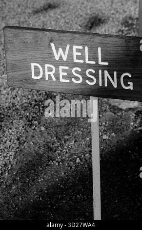 Dieses Schwarzweiß-Bild zeigt ein Schild mit der Aufschrift „WELL DRESSING“, aufgenommen während der jährlichen Well Dressing-Veranstaltung in Chesterfield, Großbritannien. Well Dressing ist ein traditioneller Brauch in Derbyshire, bei dem Brunnen mit farbenfrohem Papier und Wachs dekoriert werden. Das Bild zeigt ein Schlüsselelement dieses historischen Ereignisses. Stockfoto