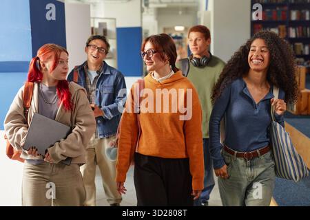 Gruppe von verschiedenen Teenagern, die zusammen laufen und im Schulflur lächeln Stockfoto