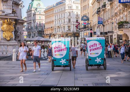 Wien, Österreich - 28. Juni 2019: Ironisches Nebeneinander kaukasischer Kinderwagen am Stephansplatz mit einer Kutschenwerbung für „Einheit in Vielfalt“. Stockfoto
