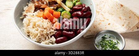 Gekochter weißer Reis, gemischt mit bunten Gemüse (Pilze, Karotten, rote Bohnen) in Schüsseln auf hellem Hintergrund. Veganes Gericht. Draufsicht. Stockfoto