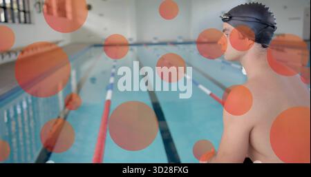 Sitzender männlicher Schwimmer am Schwimmbecken, mit Badekappe, Schutzbrille, Slip und Seilen, Kopierraum Stockfoto